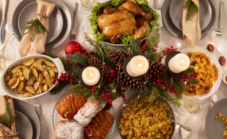 Mesa posta com comidas natalinas: peru, farofa, batata rústica e tender.